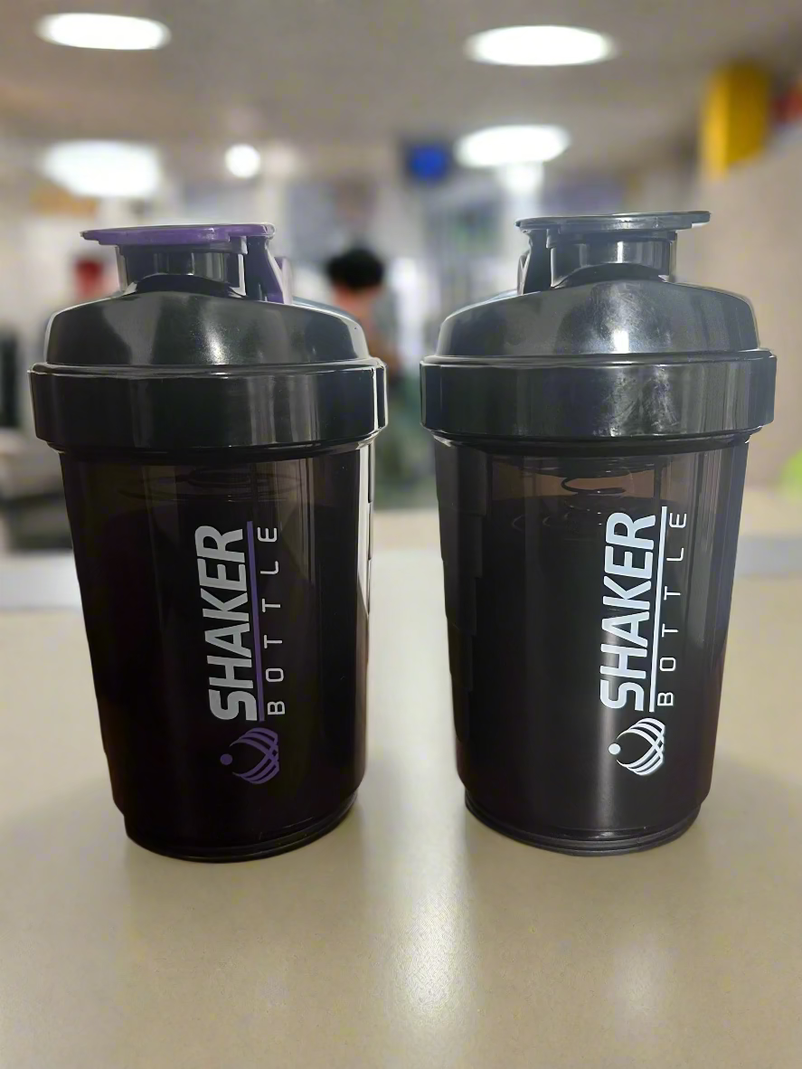 Two black shaker bottles with purple and gray accents on a wooden surface.